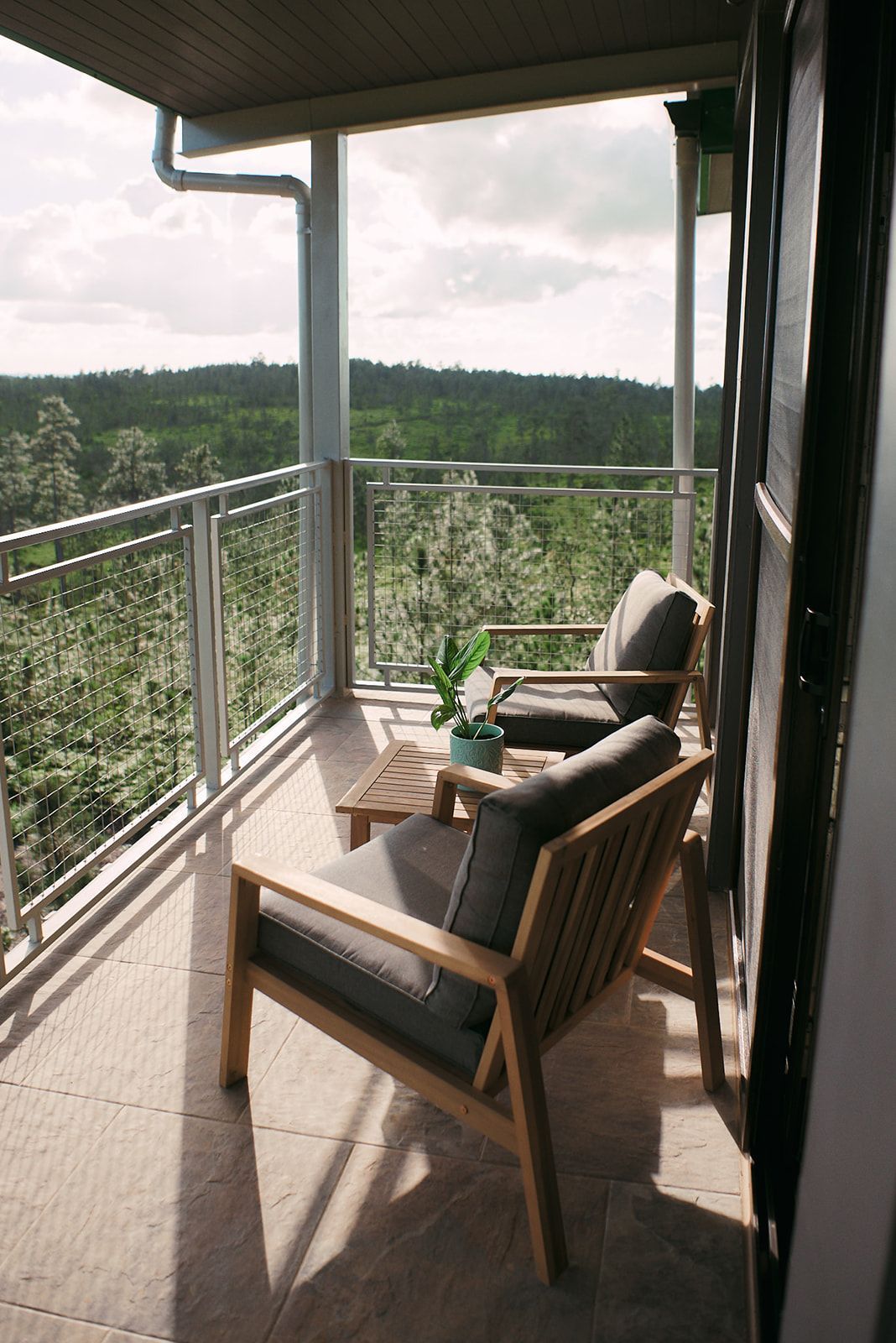 Private balcony with wooden chairs, offering scenic views of the lush greenery, ideal for romantic mornings.