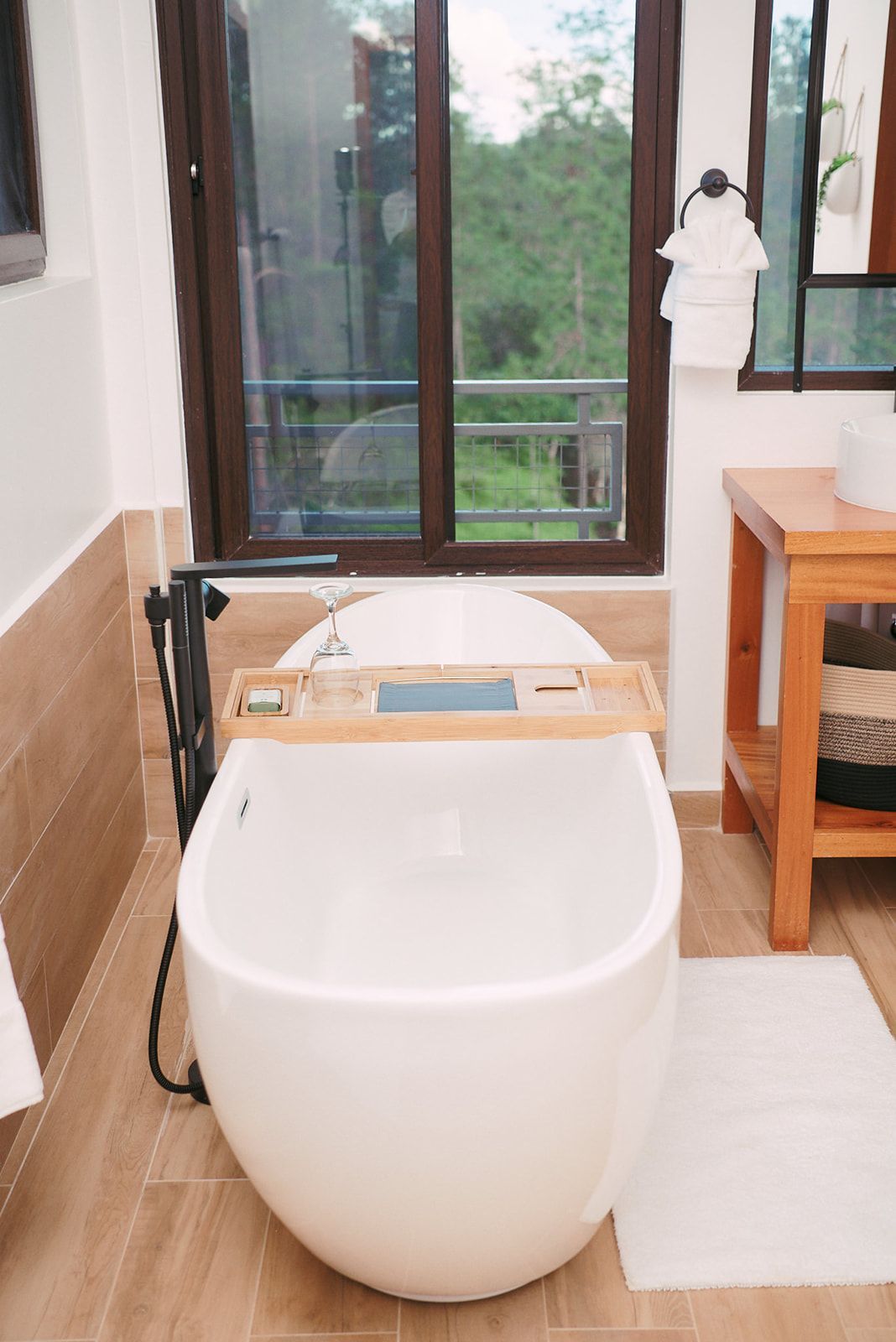 Luxurious bathroom with soaking tub and nature views through large windows, perfect for a relaxing, romantic retreat.