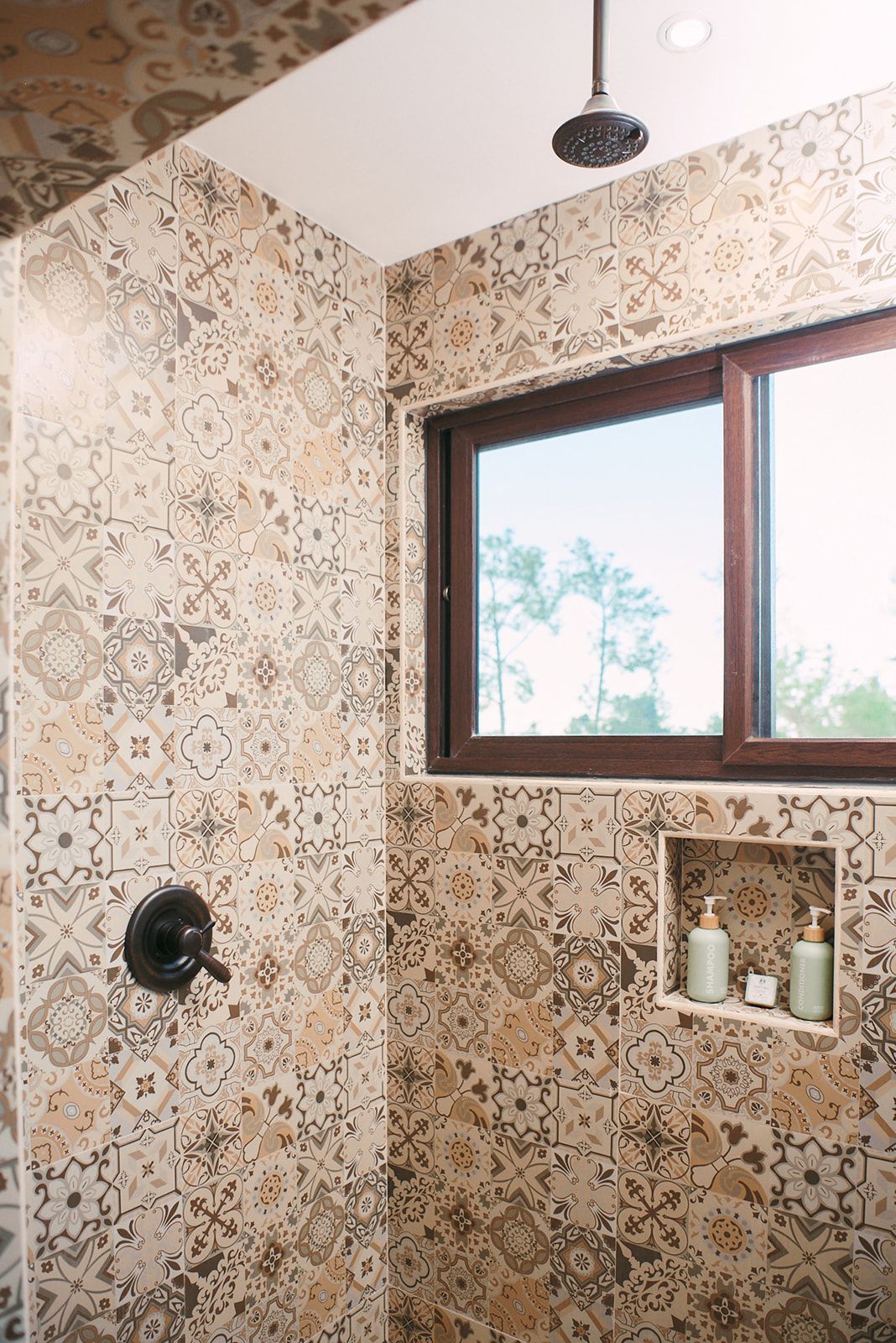 Chic walk-in shower with patterned tiles and a window offering natural light, adding to the luxury feel.