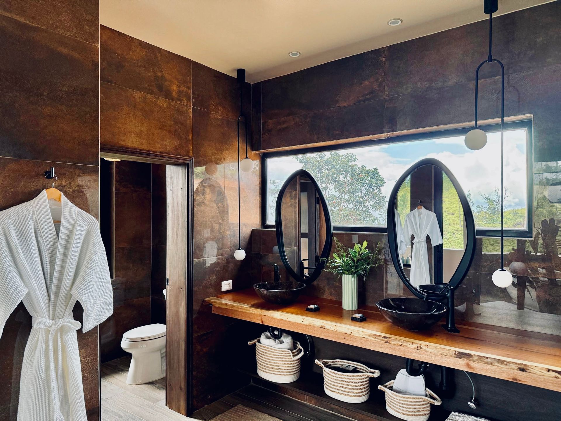 A bathroom with two sinks , two mirrors and a toilet.