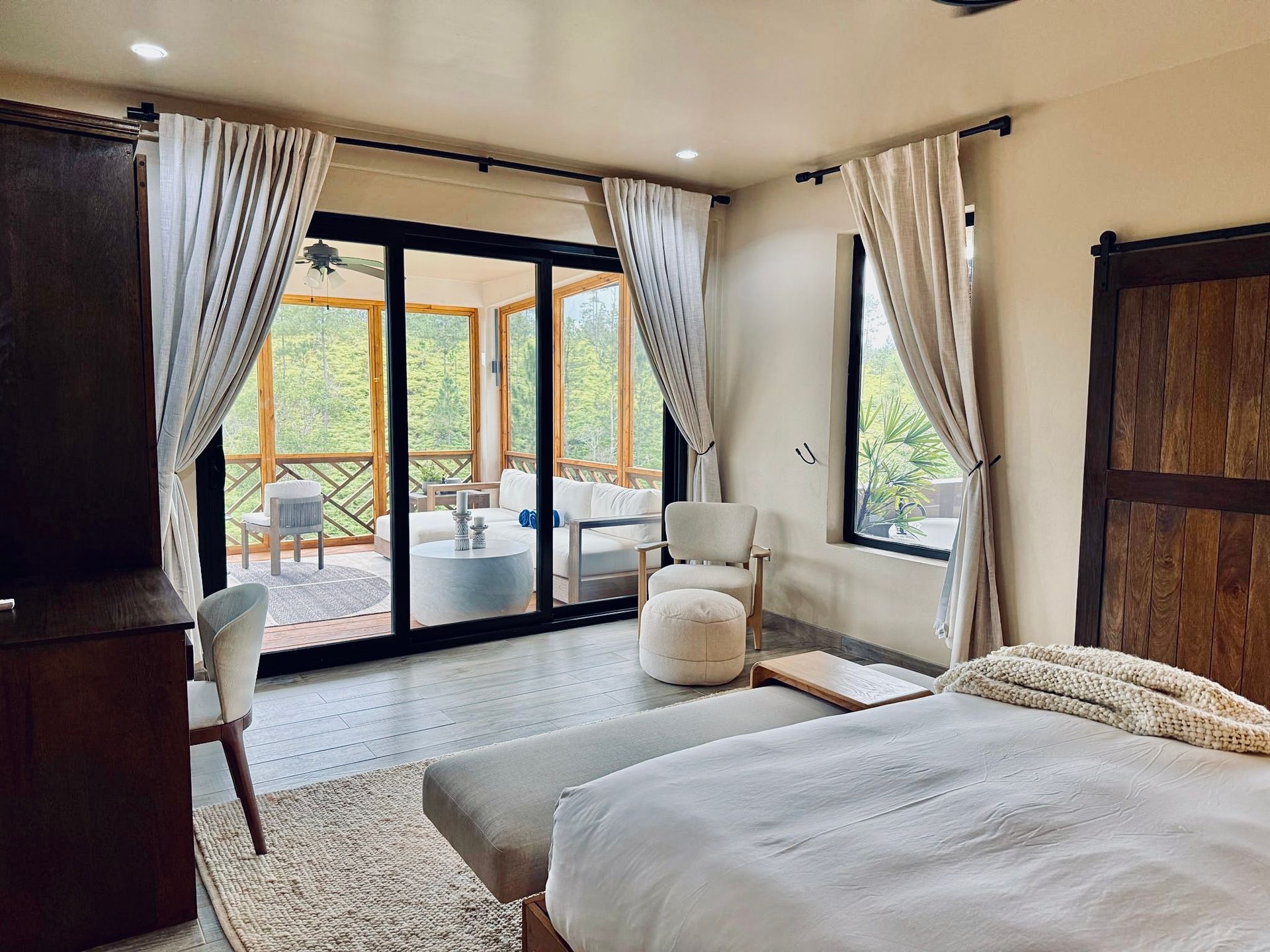 A bedroom with a bed , chairs , and sliding glass doors leading to a balcony.