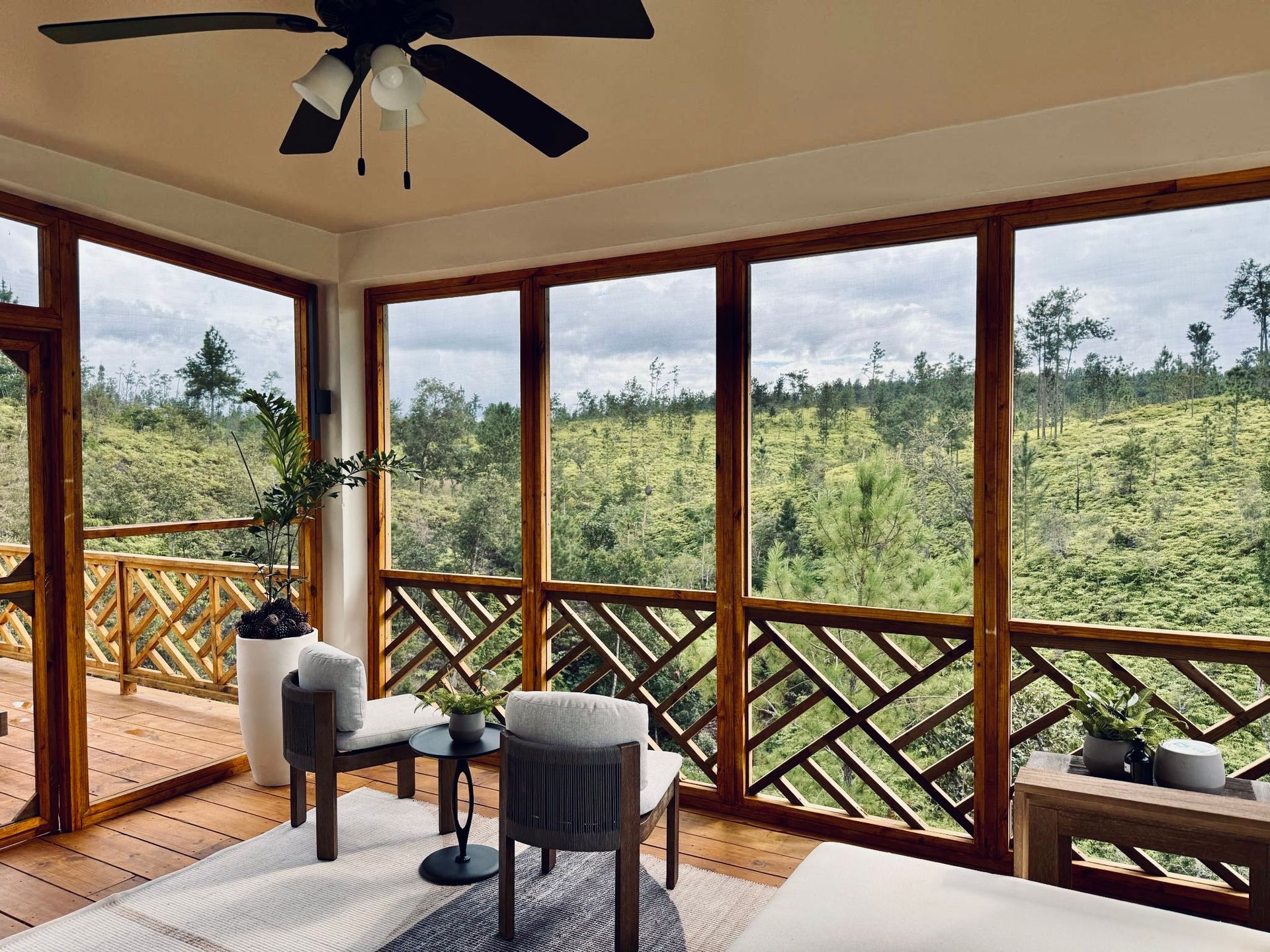 A living room with a lot of windows and a ceiling fan.