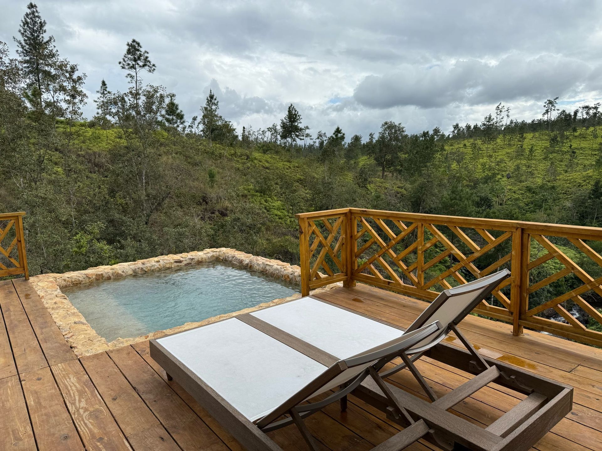 Two lounge chairs are sitting on a wooden deck next to a swimming pool.
