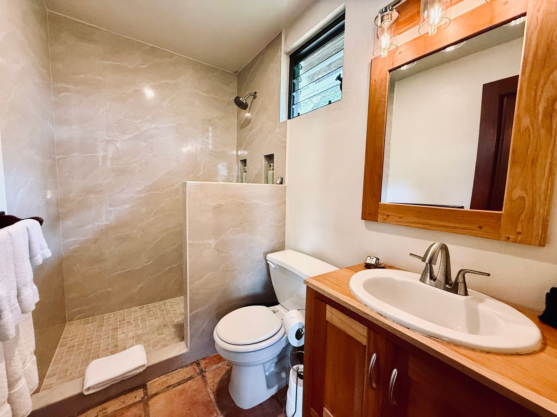 A bathroom with a toilet , sink and shower.