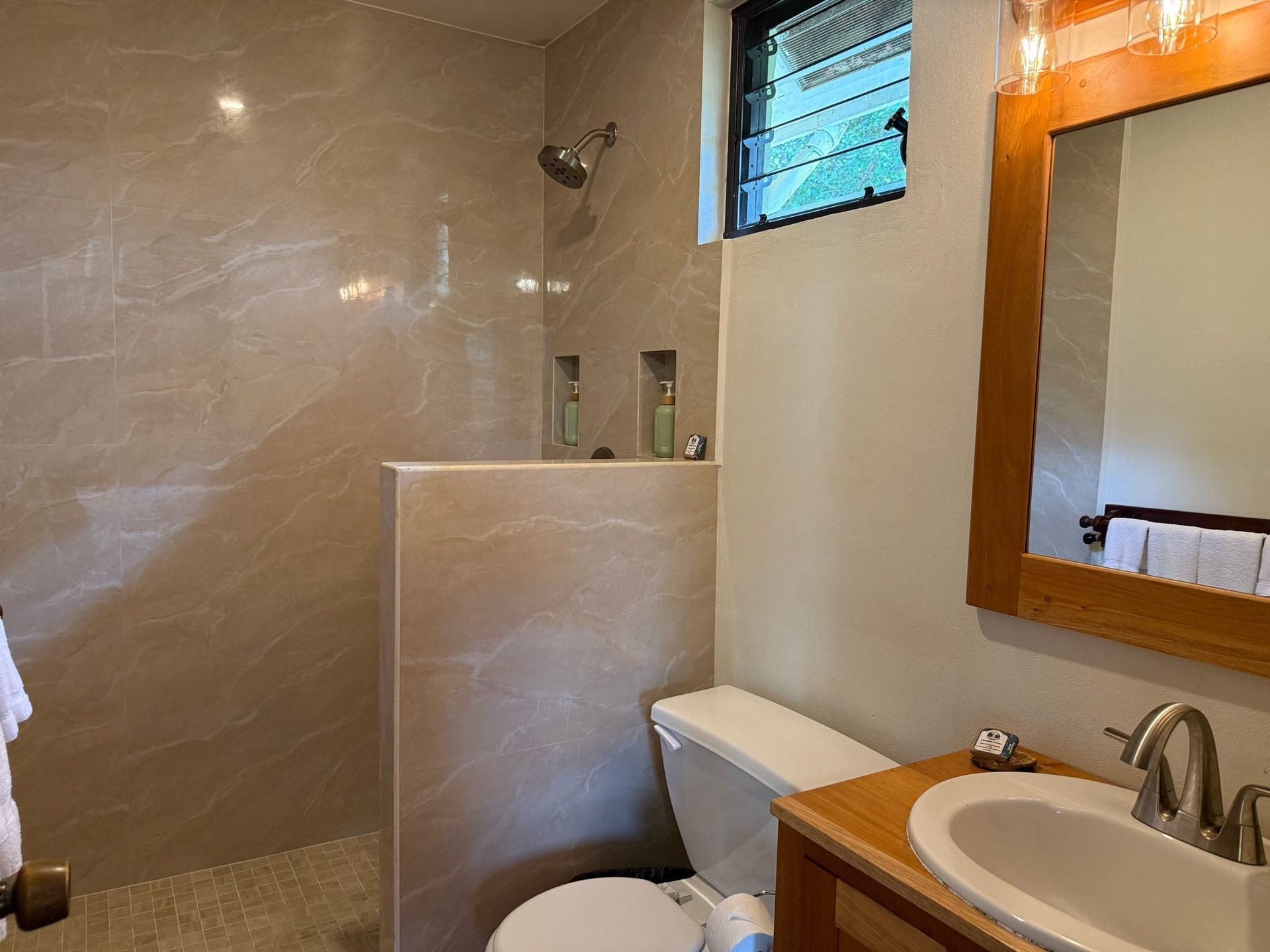 A bathroom with a toilet , sink and shower.