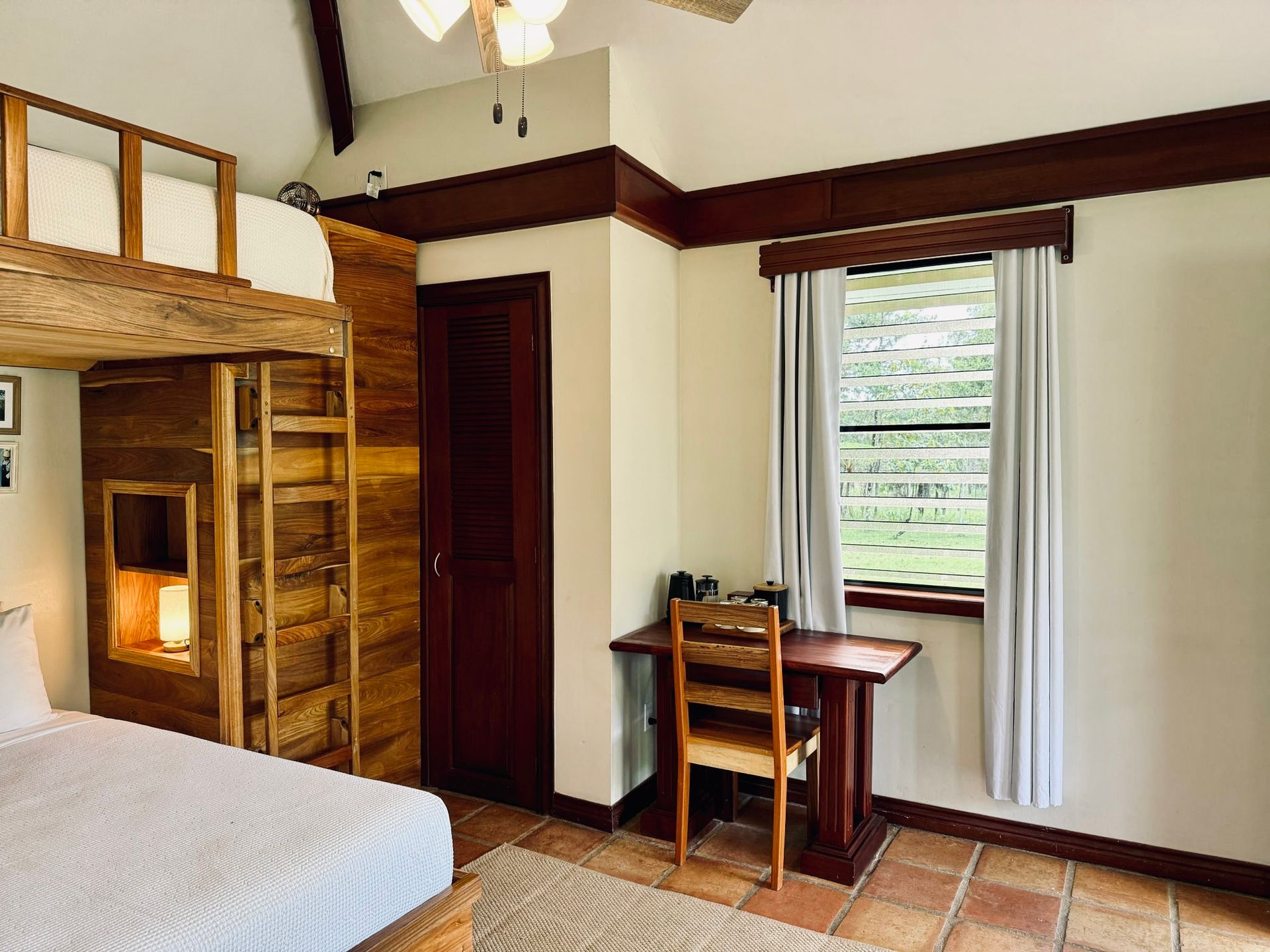 A bedroom with a bunk bed , desk and chair.