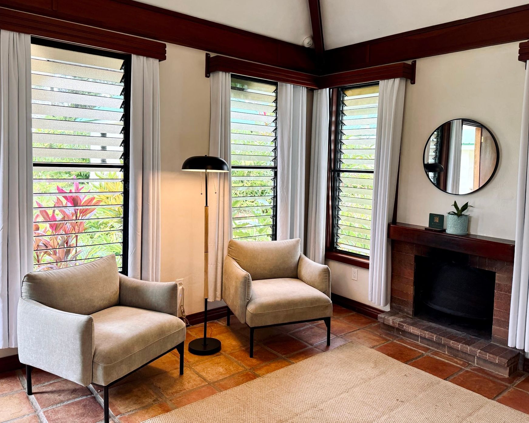 A living room with two chairs , a fireplace and a mirror.