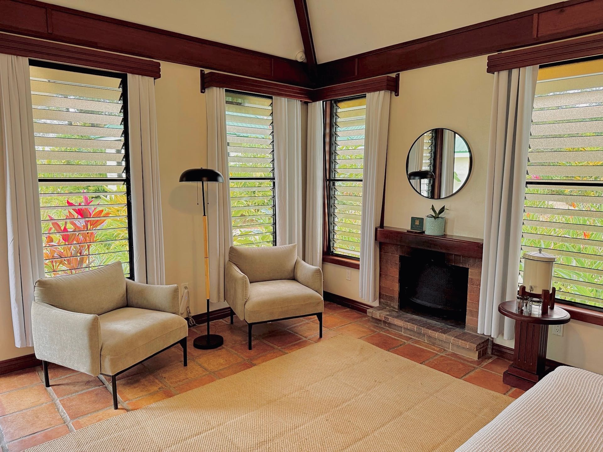 A living room with two chairs , a fireplace and a mirror.