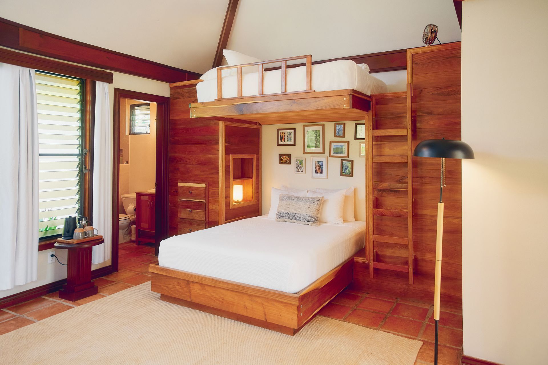 Family Cottage. Bedroom with a loft bed, wooden furniture, and framed artwork on the wall.