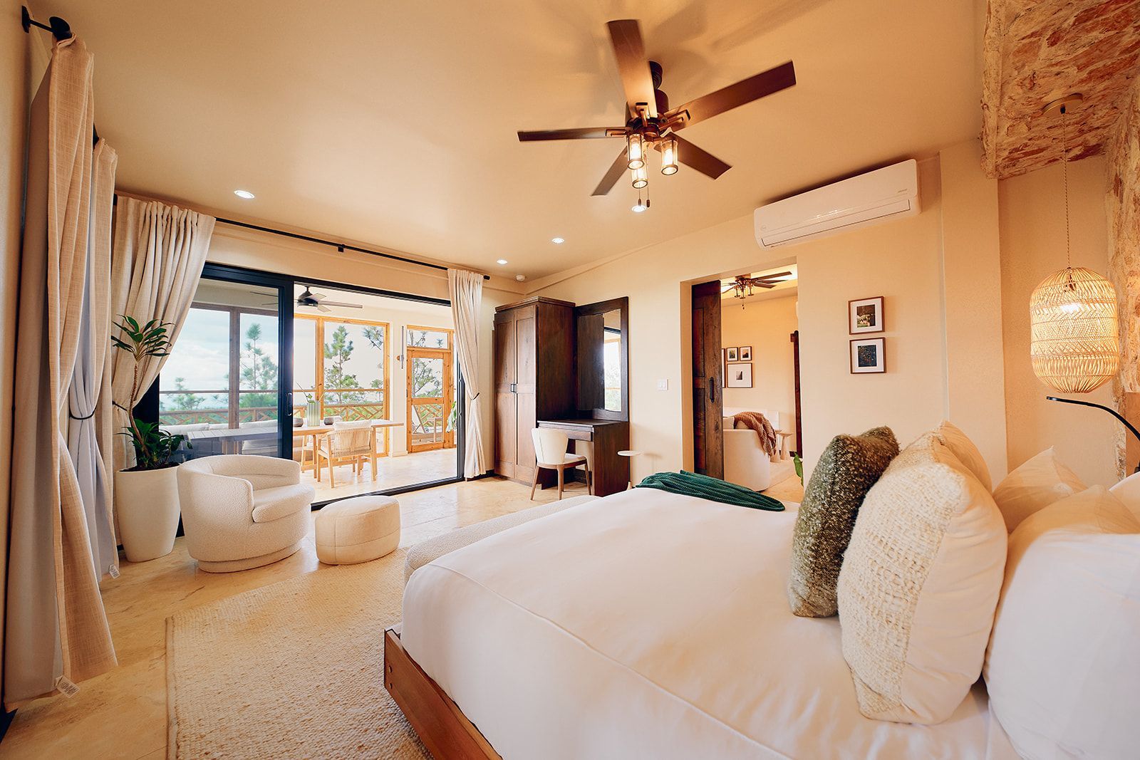 Spacious bedroom with king bed, balcony, and neutral tones. Beige walls, white rug, and ceiling fan.