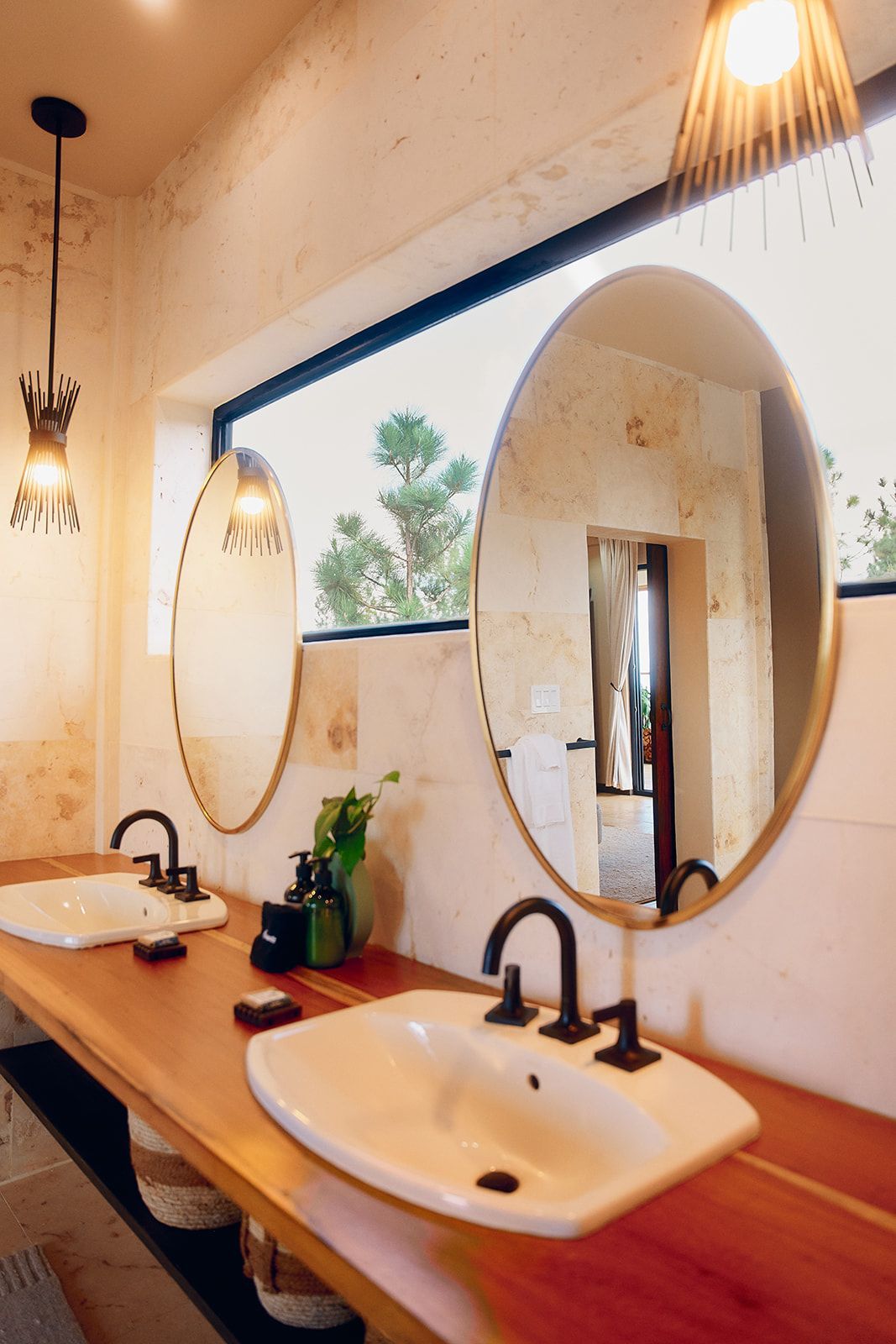 Bathroom with two sinks on a wooden counter, large mirrors, dark faucets, and overhead lights.