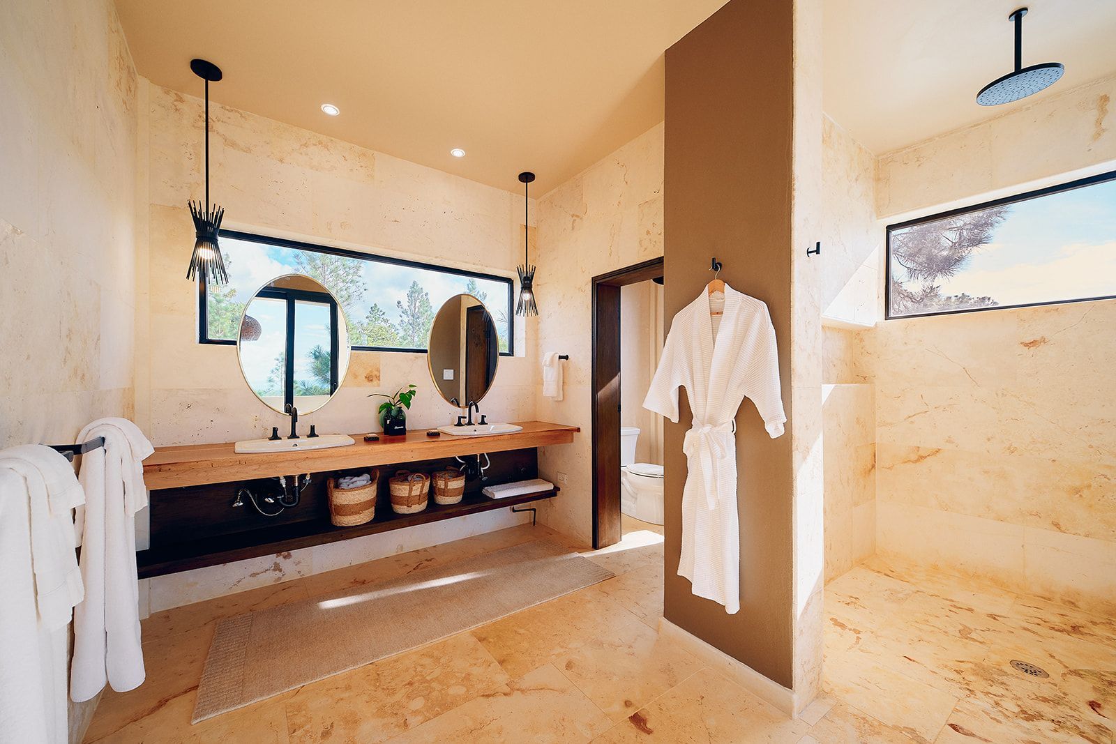 Bathroom with marble floors and walls, wooden vanity with two sinks, and a walk-in shower.