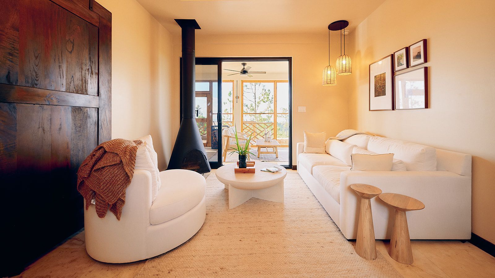 Cozy living room with a white sofa, armchair, and a fireplace, with a view of the outdoors.