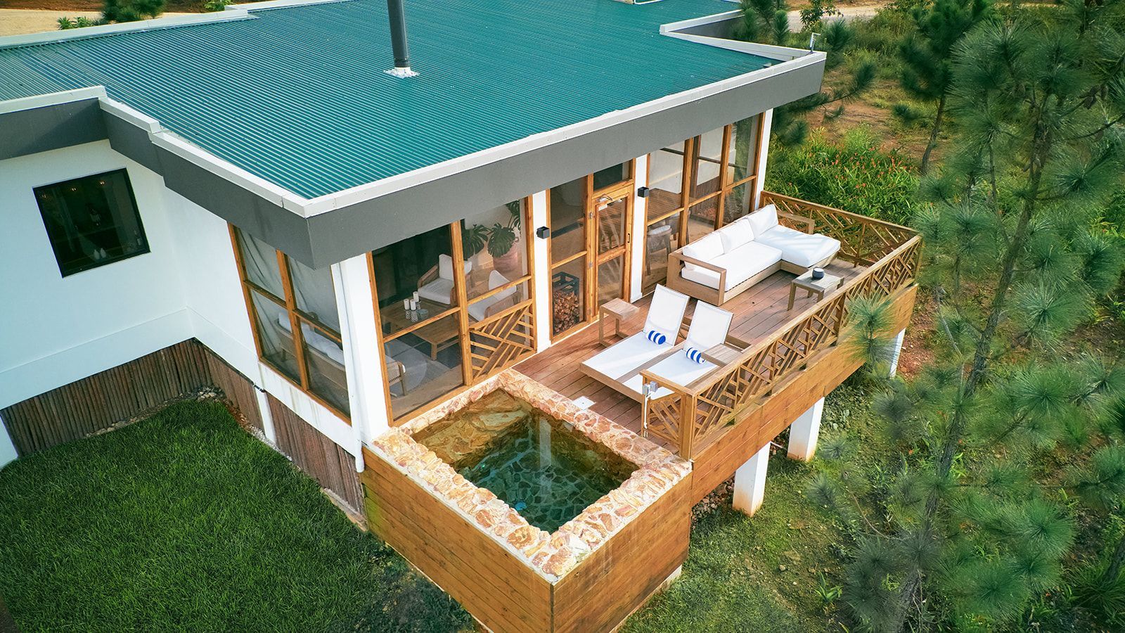 Modern house with balcony, pool, and green roof in a natural setting.