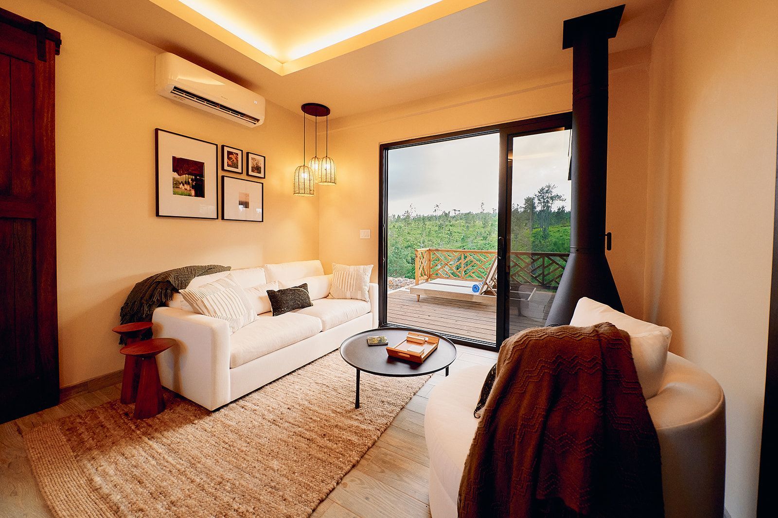 Cozy living room with white sofa, rug, and modern fireplace. Sliding glass doors lead to an outdoor area.