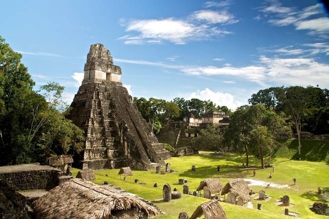 A large pyramid in the middle of a field with trees in the background