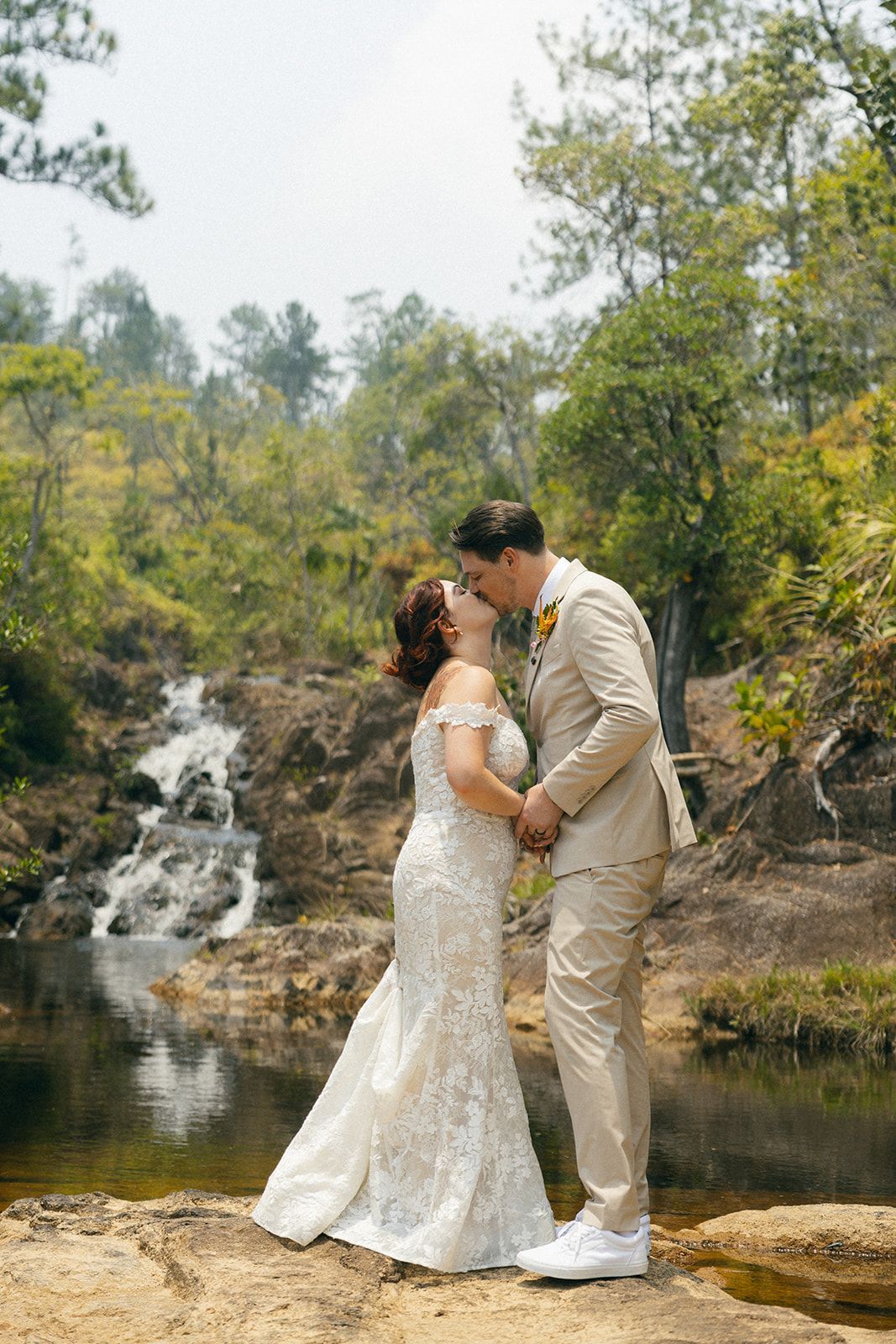 A romantic kiss by the waterfall as a newlywed couple enjoys their intimate destination wedding at Hidden Valley.