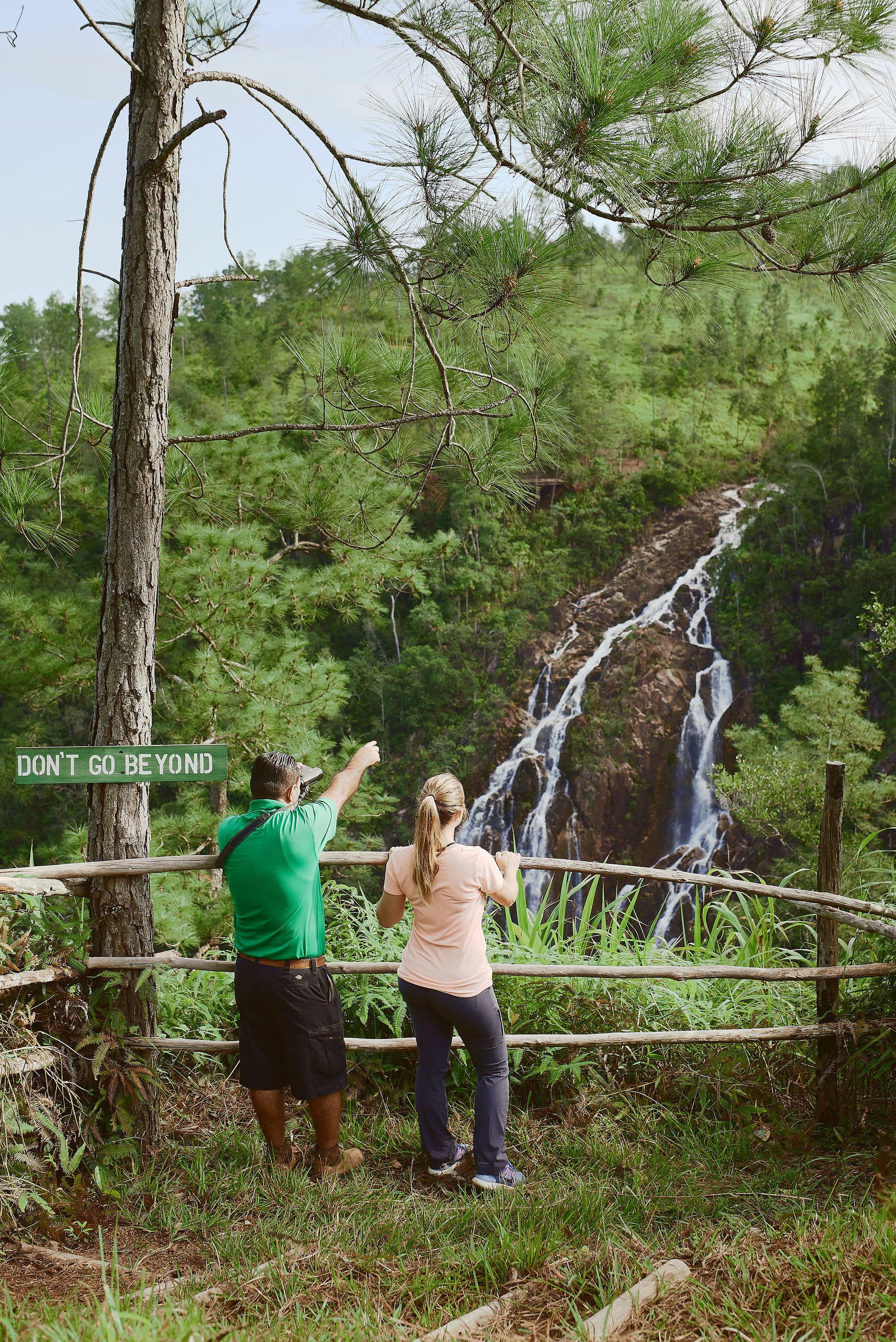 A man and a woman are standing in front of a waterfall.
