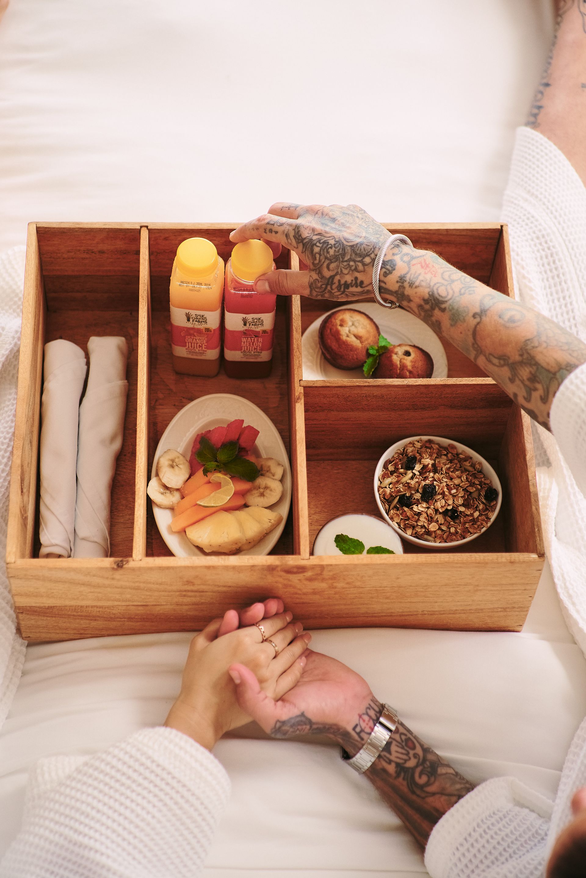 A man and woman are holding hands over a wooden tray of food.