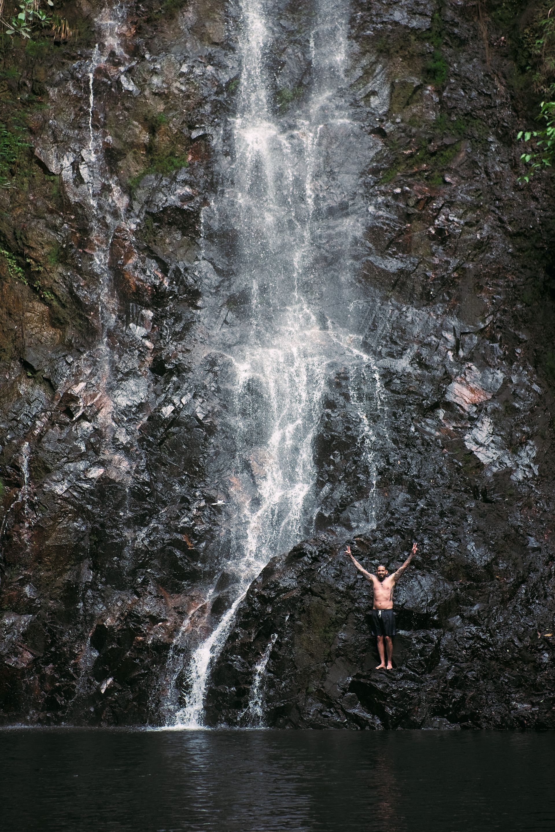 A man is jumping into a body of water from a waterfall.