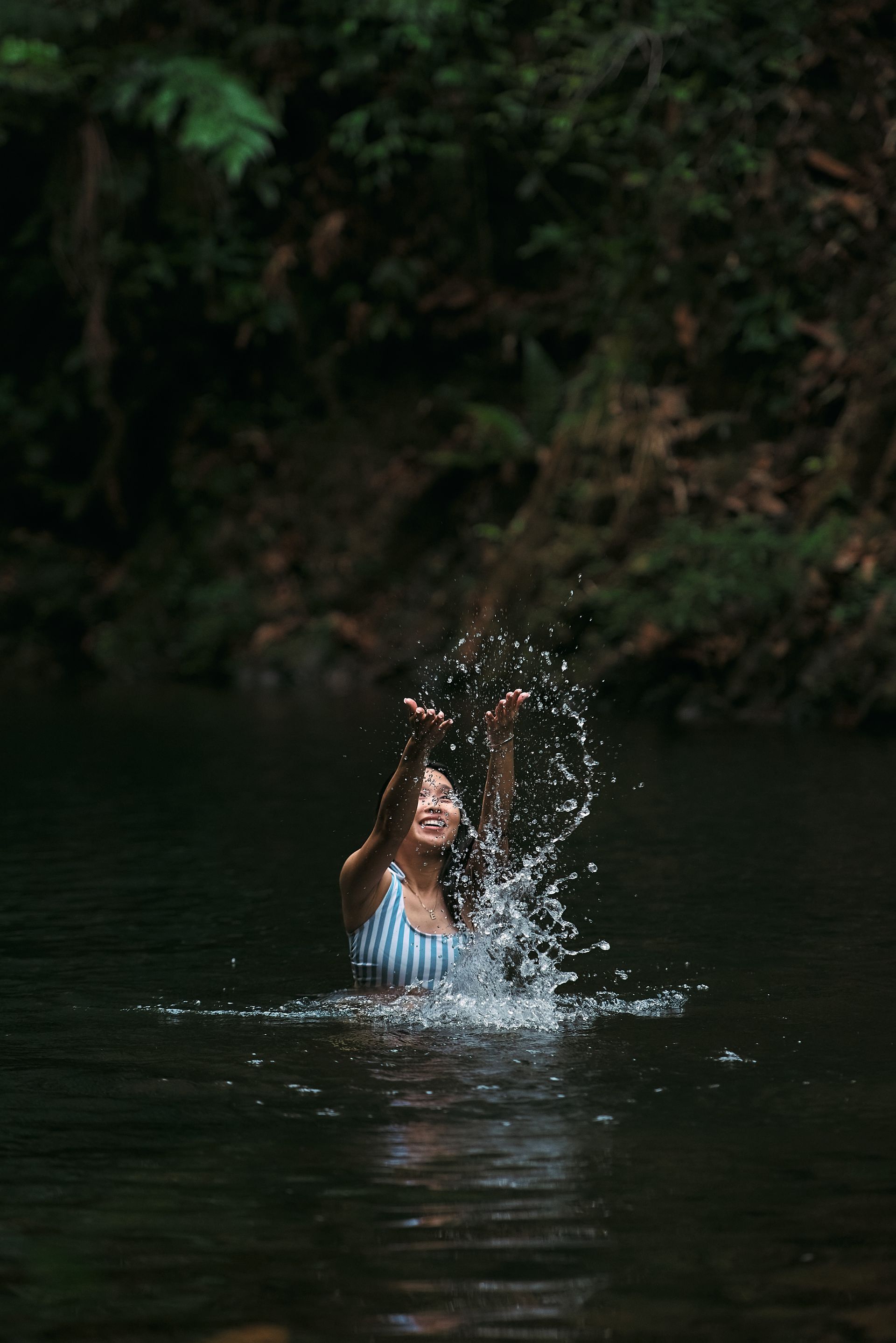 A woman is splashing water in a river.