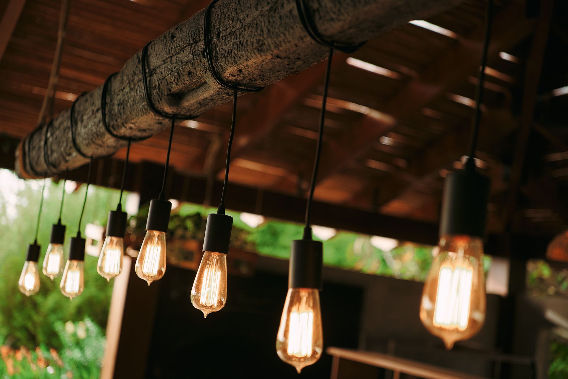 A string of light bulbs hanging from the ceiling of a wooden structure.