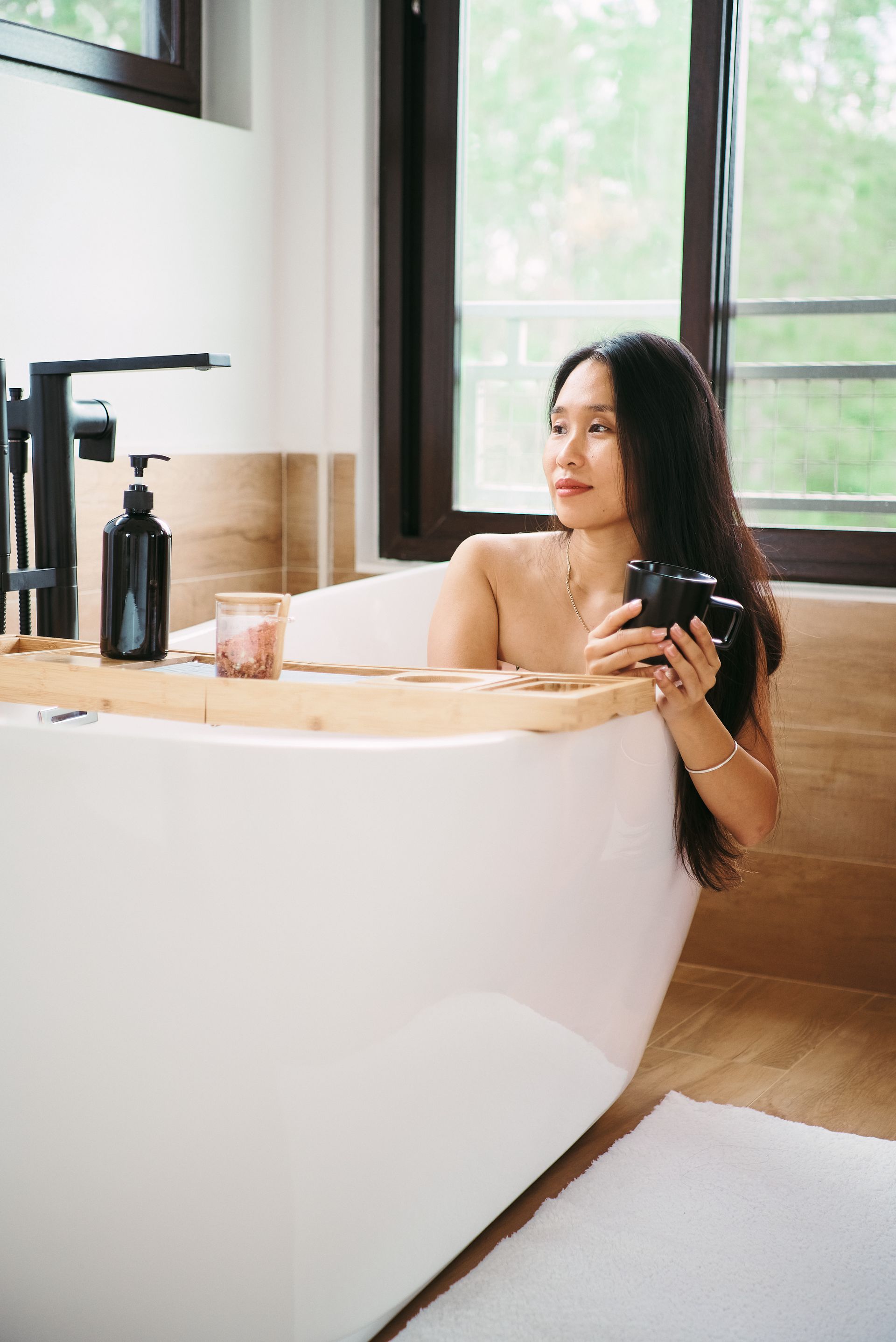 A woman is taking a bath in a bathtub and holding a camera.