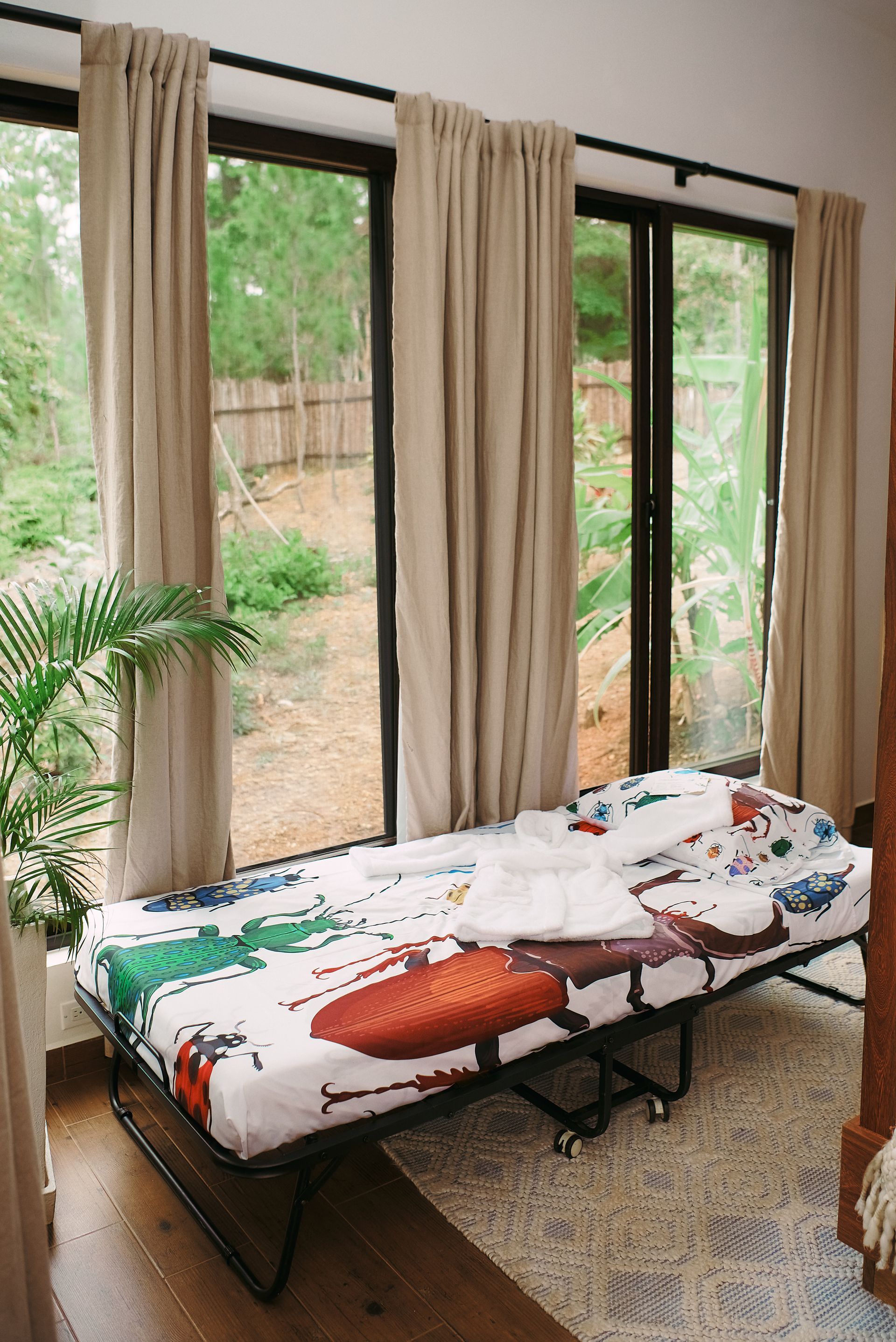 A folding bed is sitting in a room next to a window.