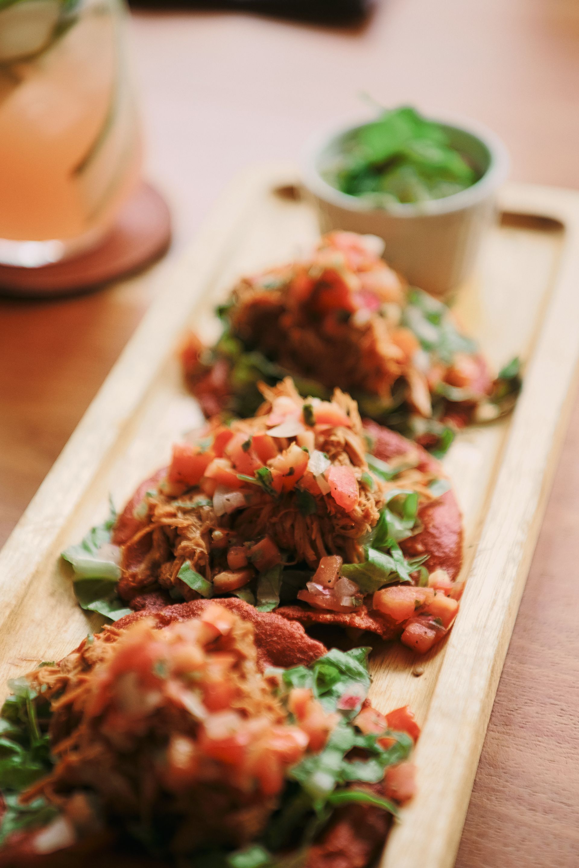 A close up of a wooden tray filled with food on a table.