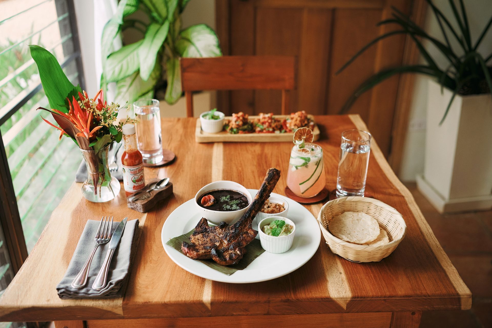 A wooden table topped with plates of food and drinks.