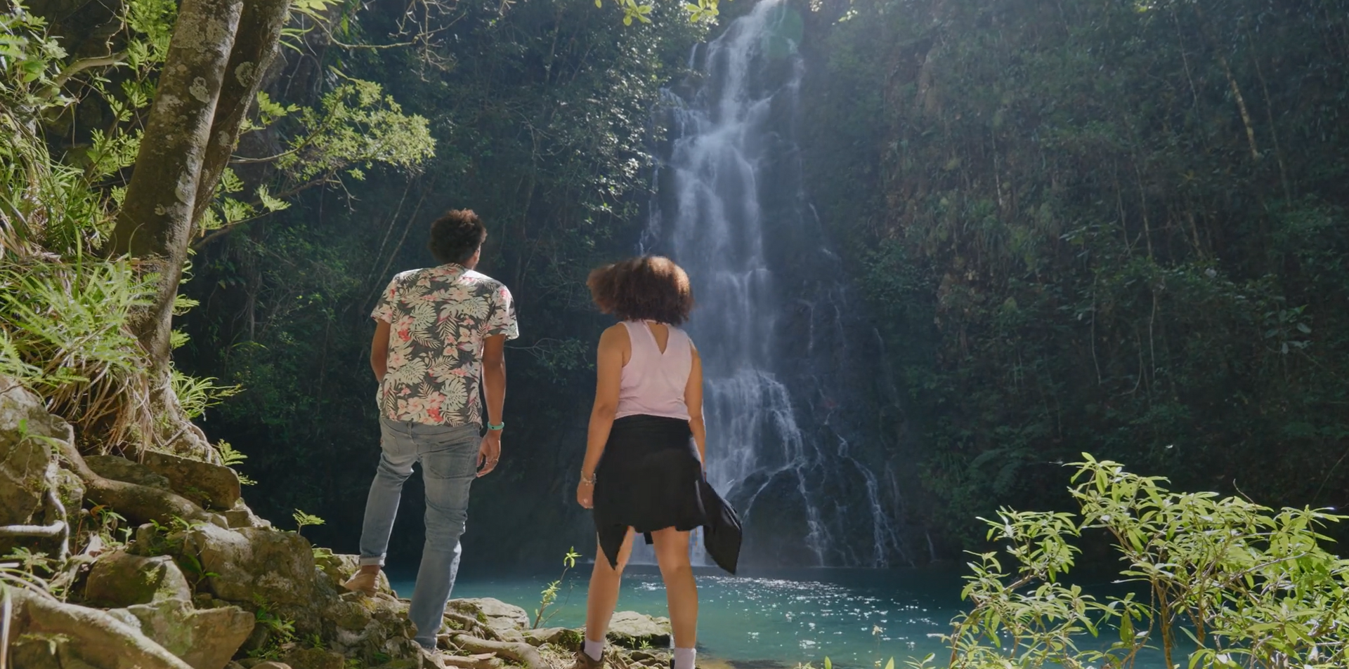 A couple stands in awe of Butterfly Falls, surrounded by lush jungle, capturing the essence of adventure and natural beauty.