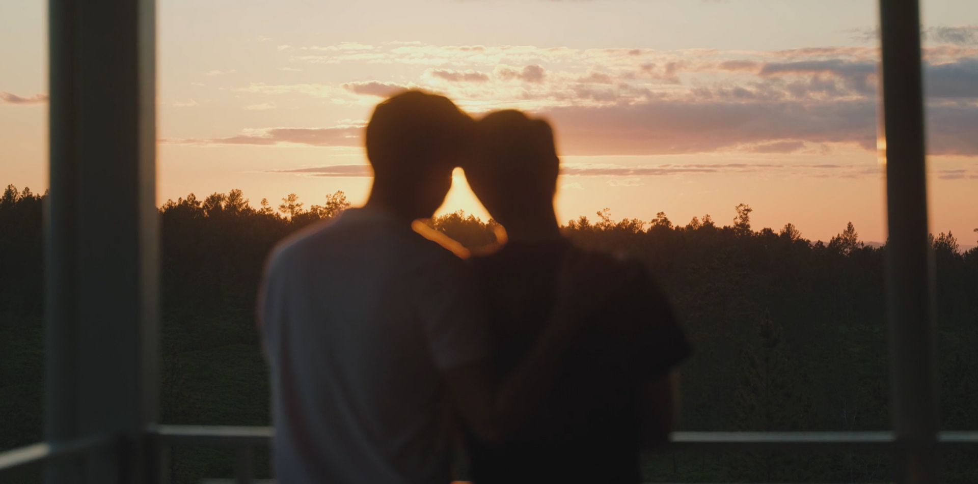 LGBTQ+ couple enjoying a serene sunset during their getaway, surrounded by the beauty of Belize’s forested landscape.