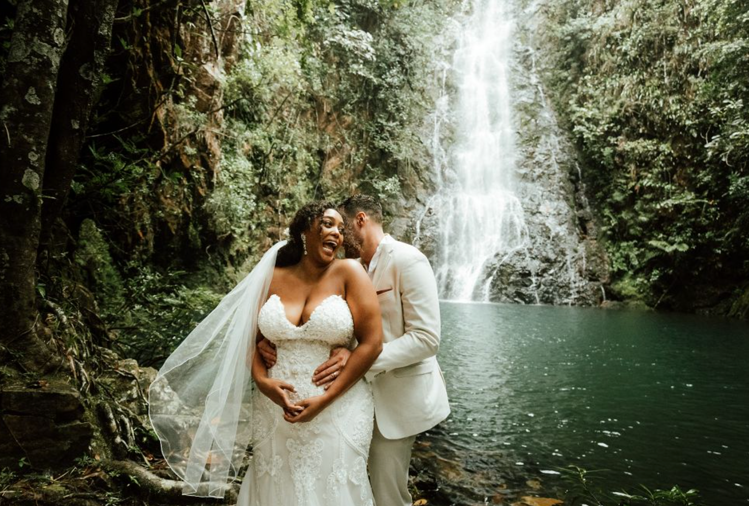 A couple shares a special moment during their wedding at Butterfly Falls, with the serene waterfall in the background.