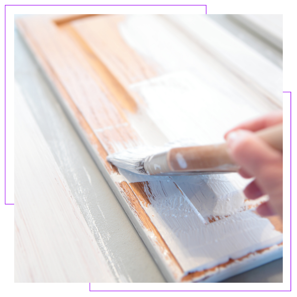 A person is painting a piece of wood with a brush.