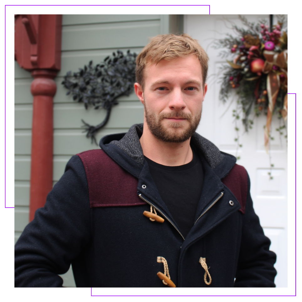 A man with a beard is wearing a black coat