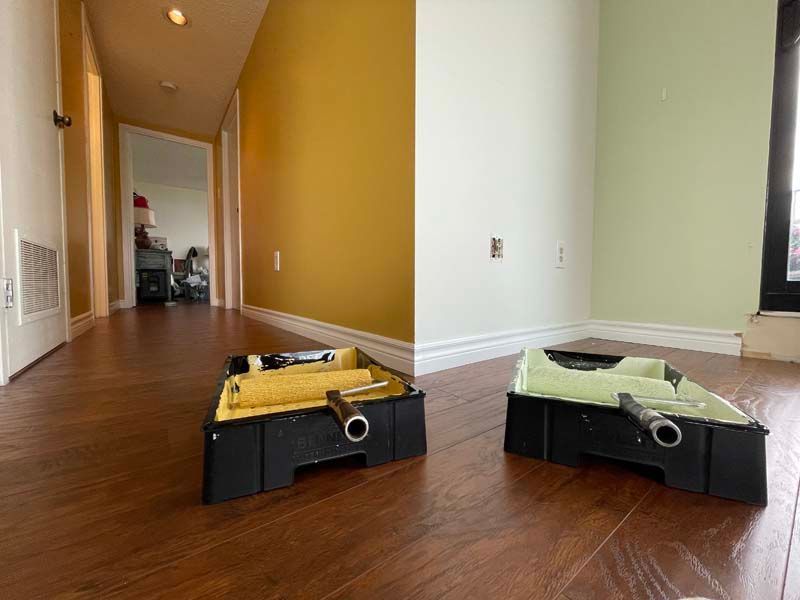 Two boxes of tools are sitting on a wooden floor in an empty room.