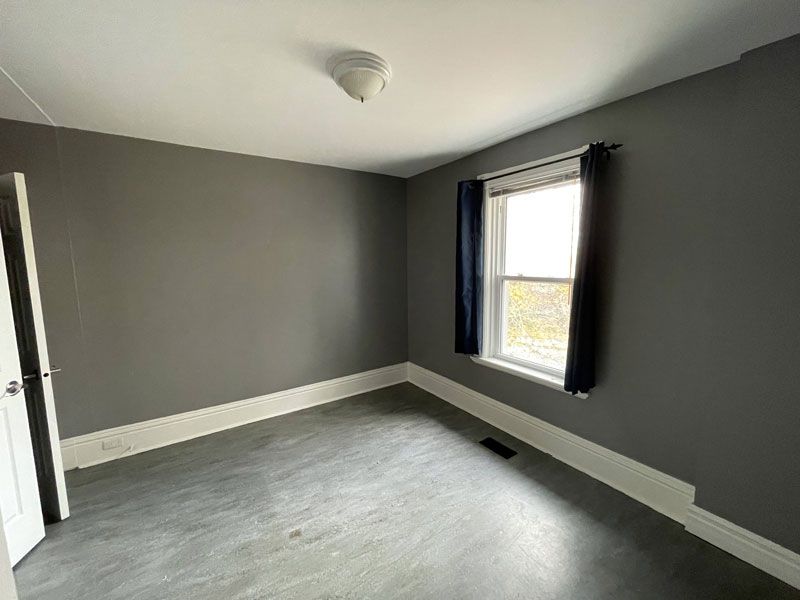 an empty bedroom with gray walls and a window .