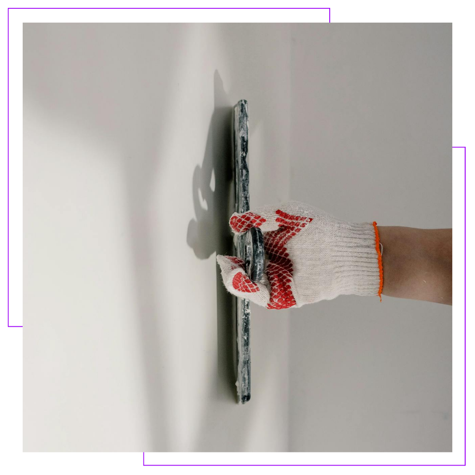 A person is plastering a wall with a trowel.