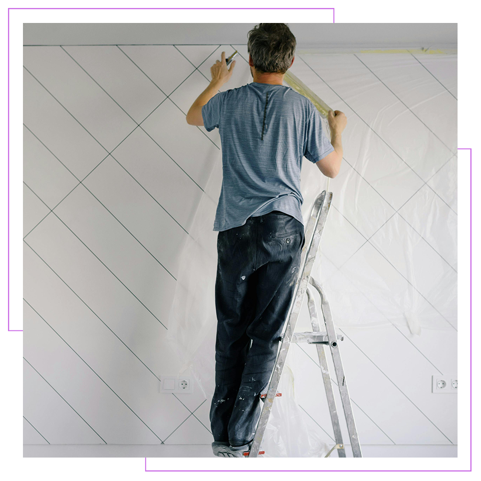 a man is standing on a ladder painting on a wall. 