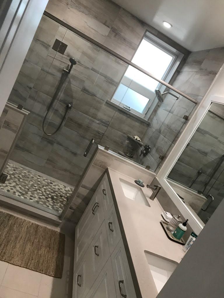 A bathroom with a walk in shower , sink and mirror.