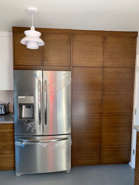 A stainless steel refrigerator in a kitchen with wooden cabinets