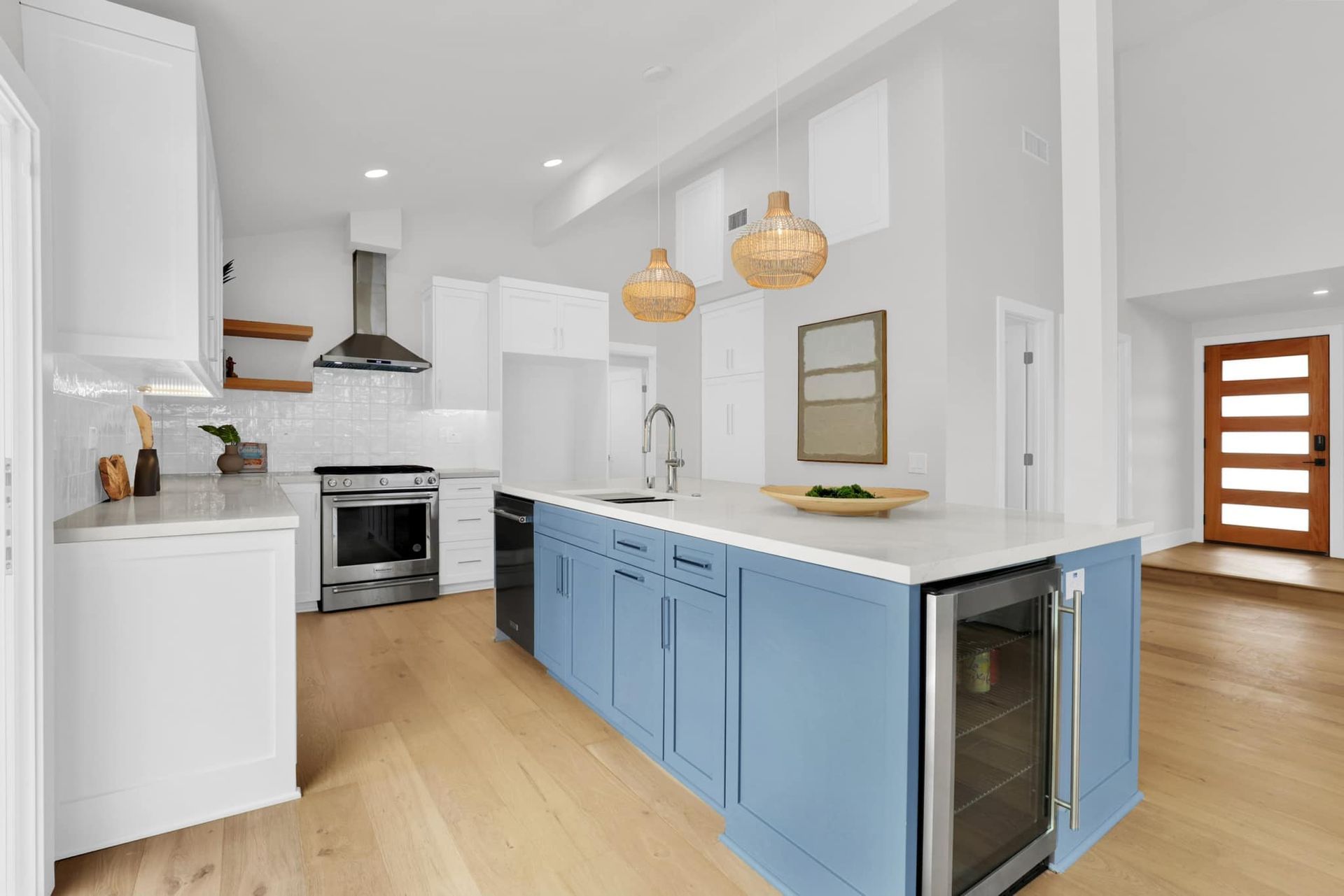 A kitchen with blue cabinets , white cabinets , stainless steel appliances and a large island.