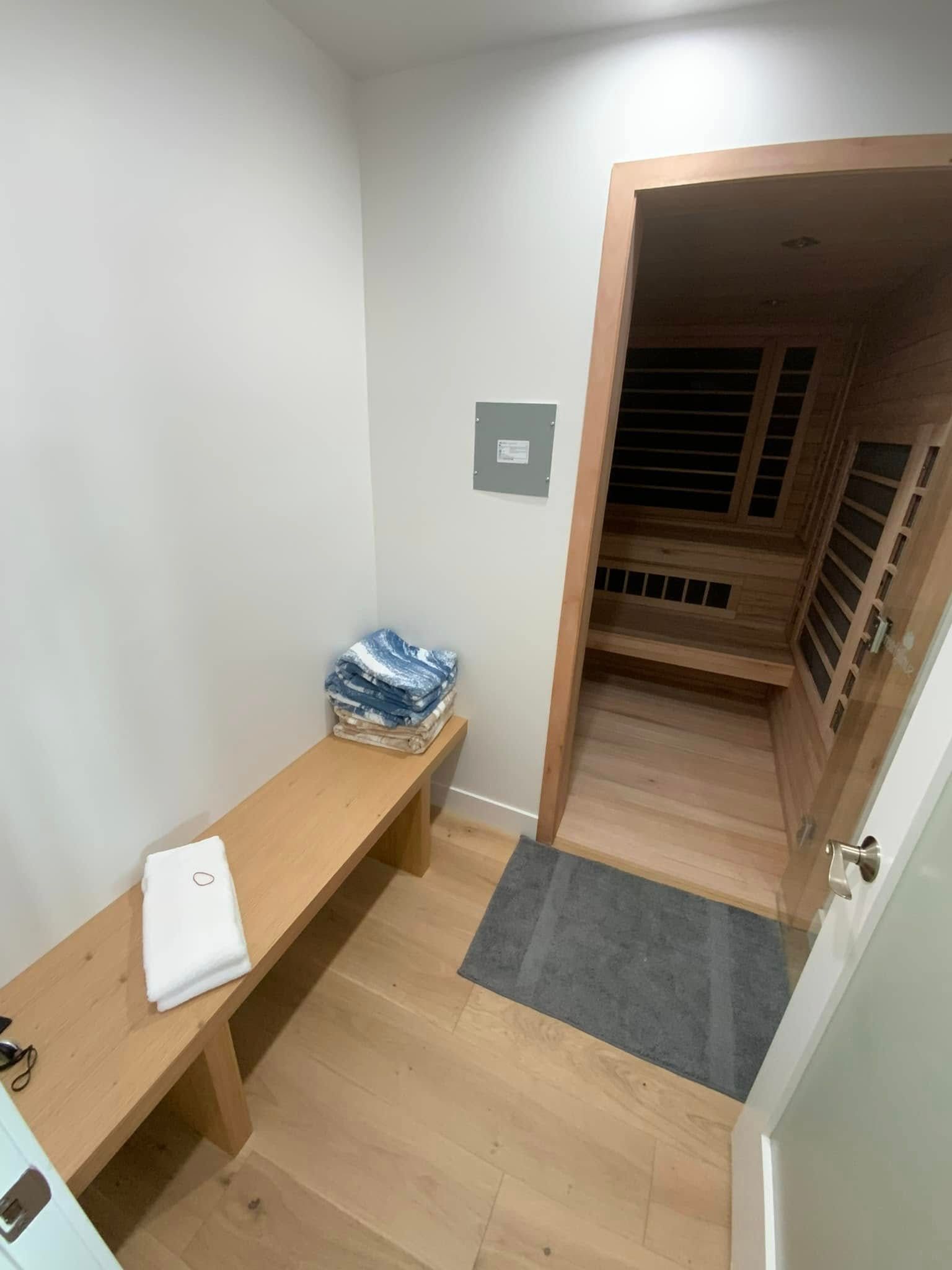 A room with a bench and a door leading to a sauna.