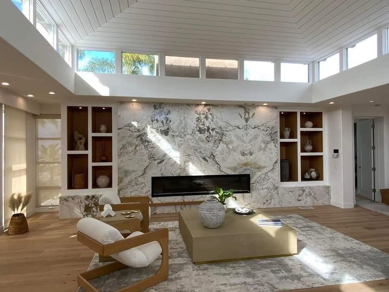 A living room with a fireplace and a marble wall