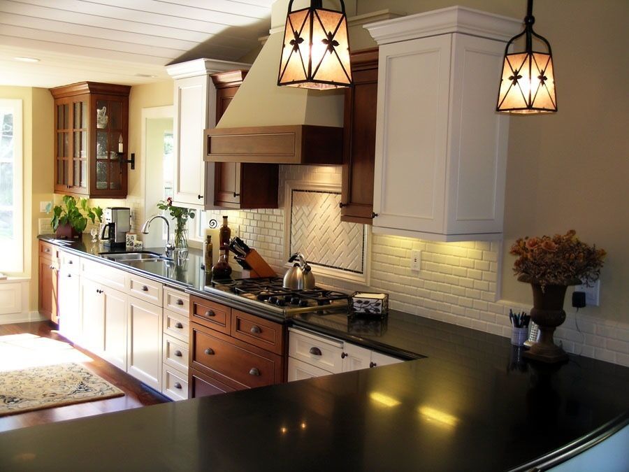 A kitchen with white cabinets and black counter tops