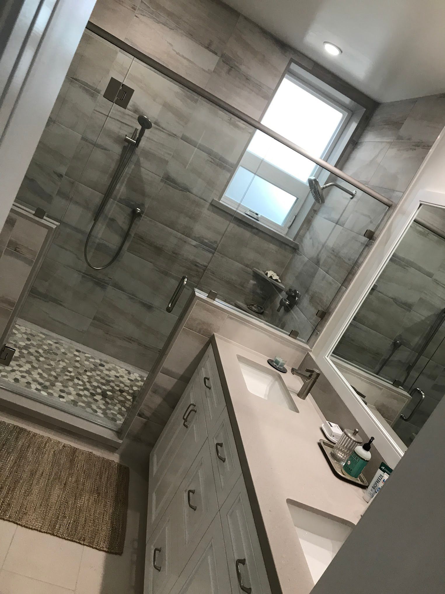 A bathroom with a walk in shower , sink and mirror.