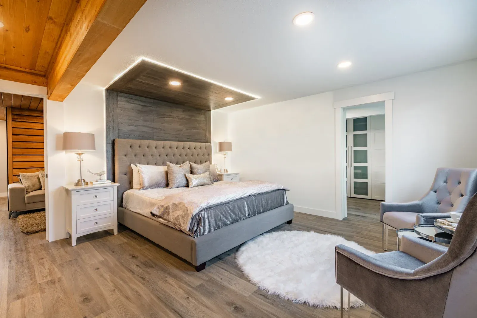 A bedroom with a large bed , chair , nightstand and rug.