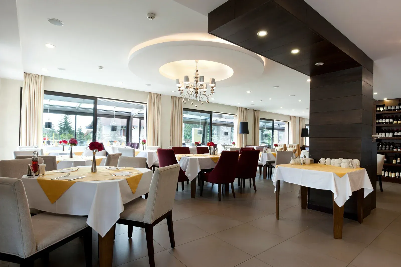 A restaurant with tables and chairs and a chandelier hanging from the ceiling.