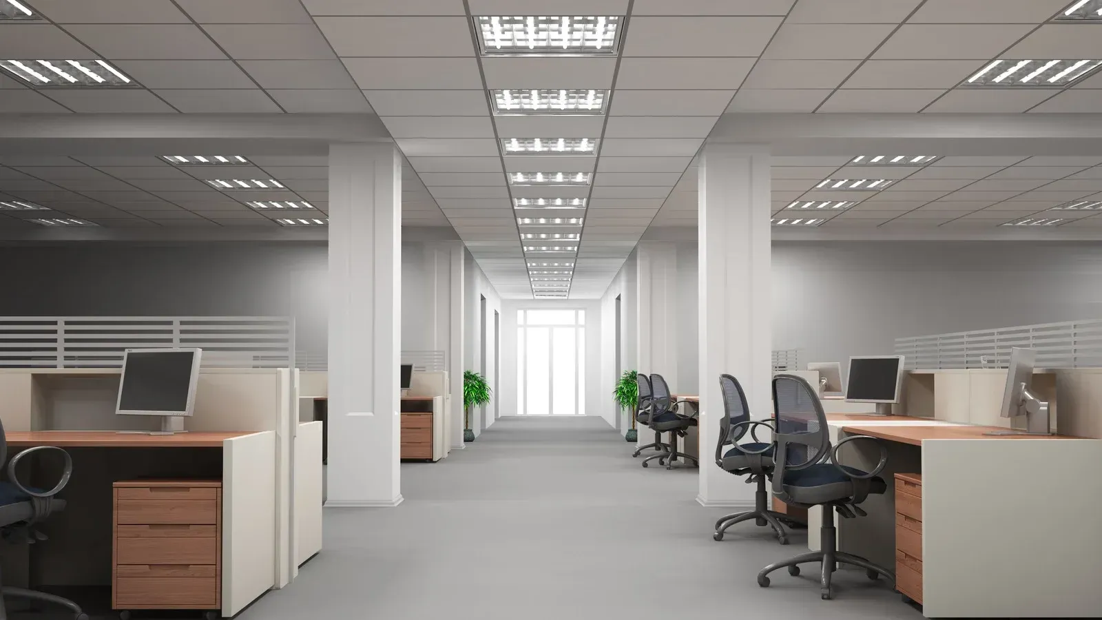 An empty office with cubicles , desks , chairs and computers.