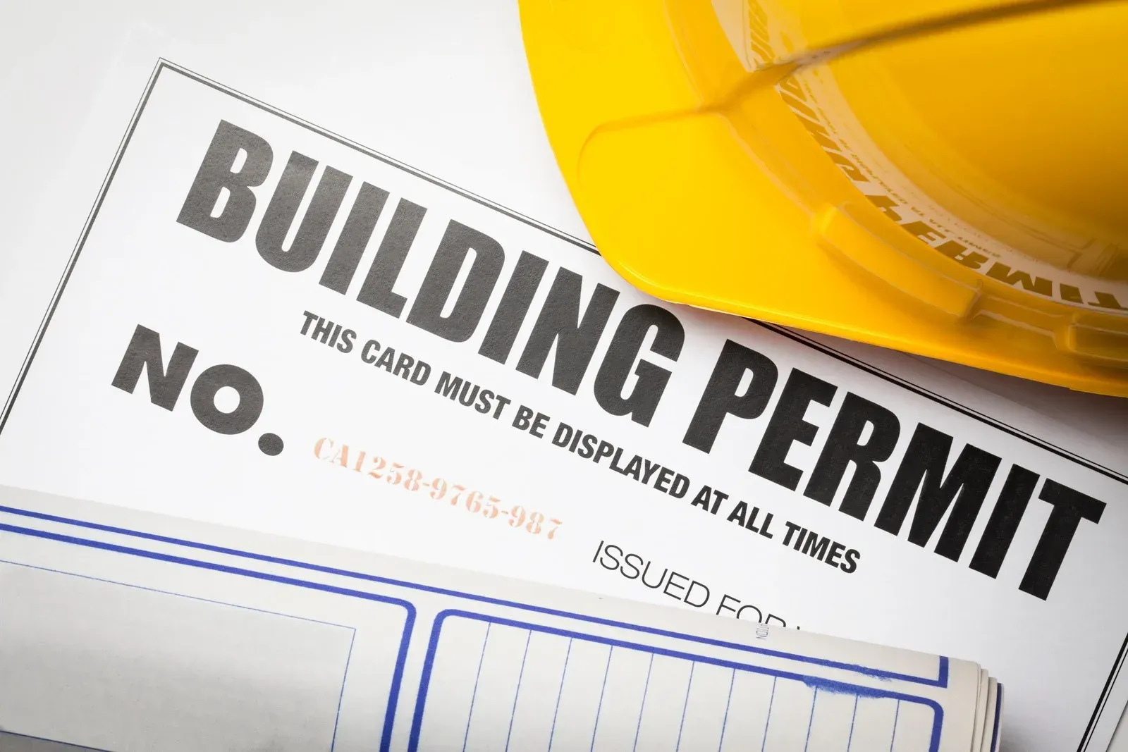 A yellow hard hat sits next to a building permit